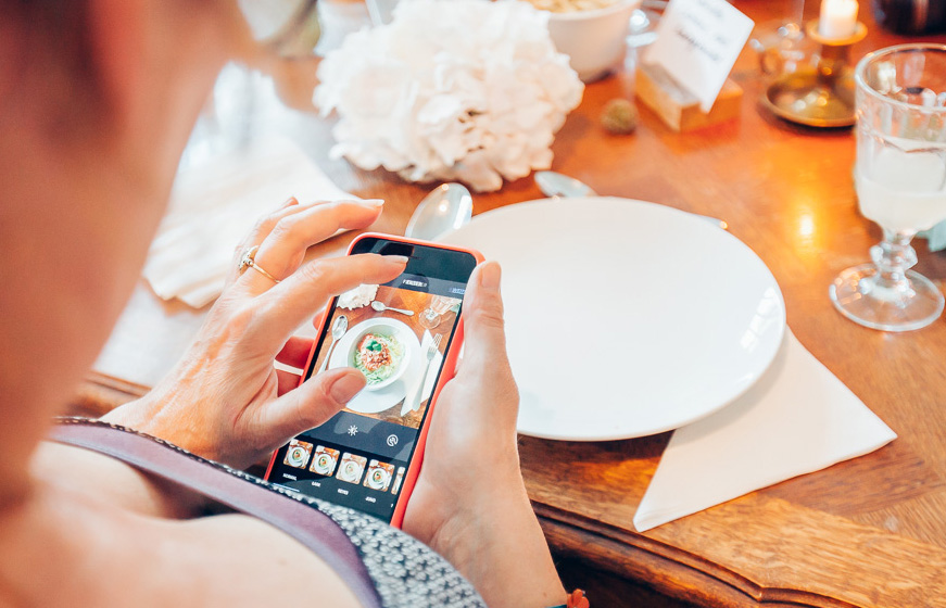 Frau mit Handy fotografiert Essen