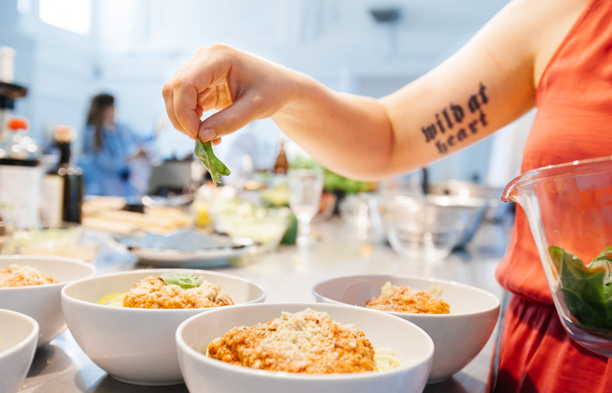 Frau streut etwas über Schüsseln mit Essen